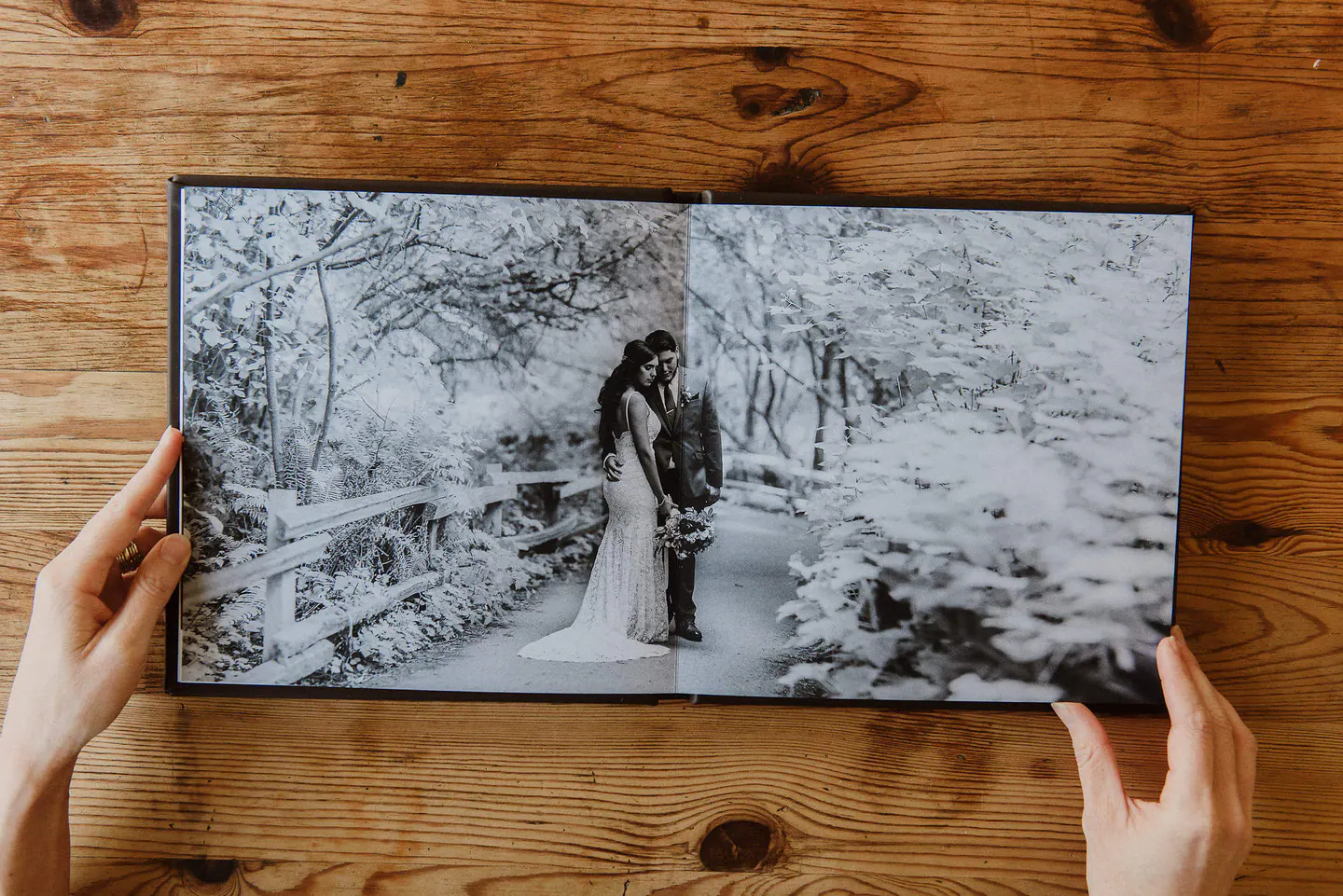 Hands turning a panoramic fine-art wedding album spread