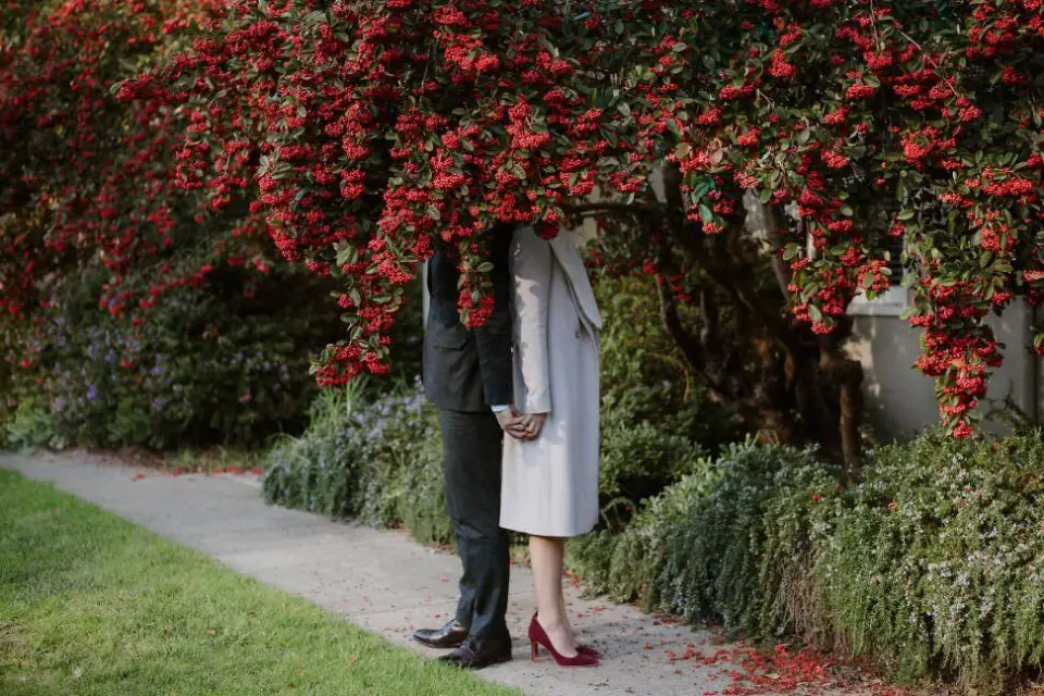 A bride waiting beneath red flowers before an intimate ceremony