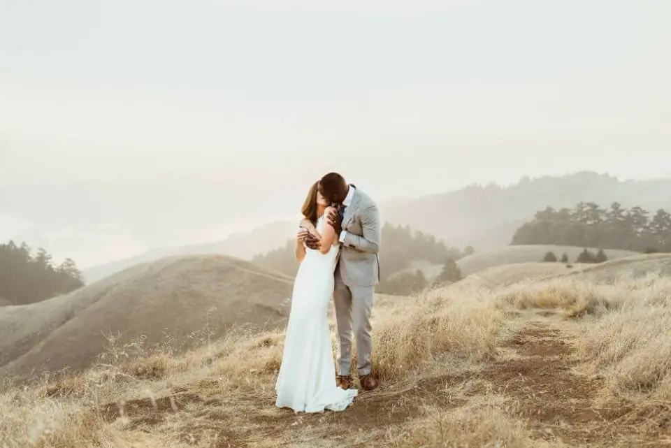 Newlyweds together on a golden coastal hillside