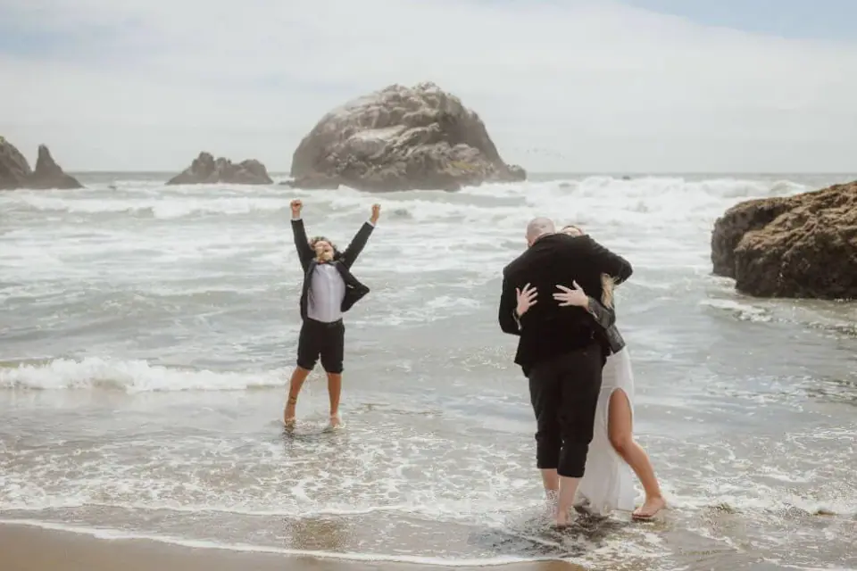 An eloping couple laughing at the edge of the Pacific
