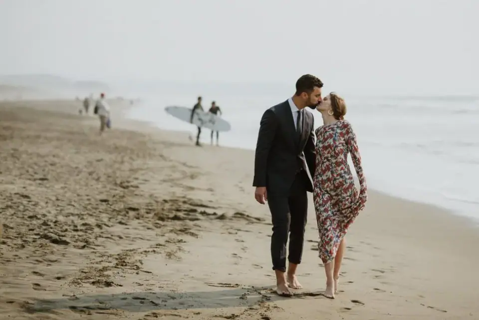 A small-wedding couple walking with their dogs on the beach