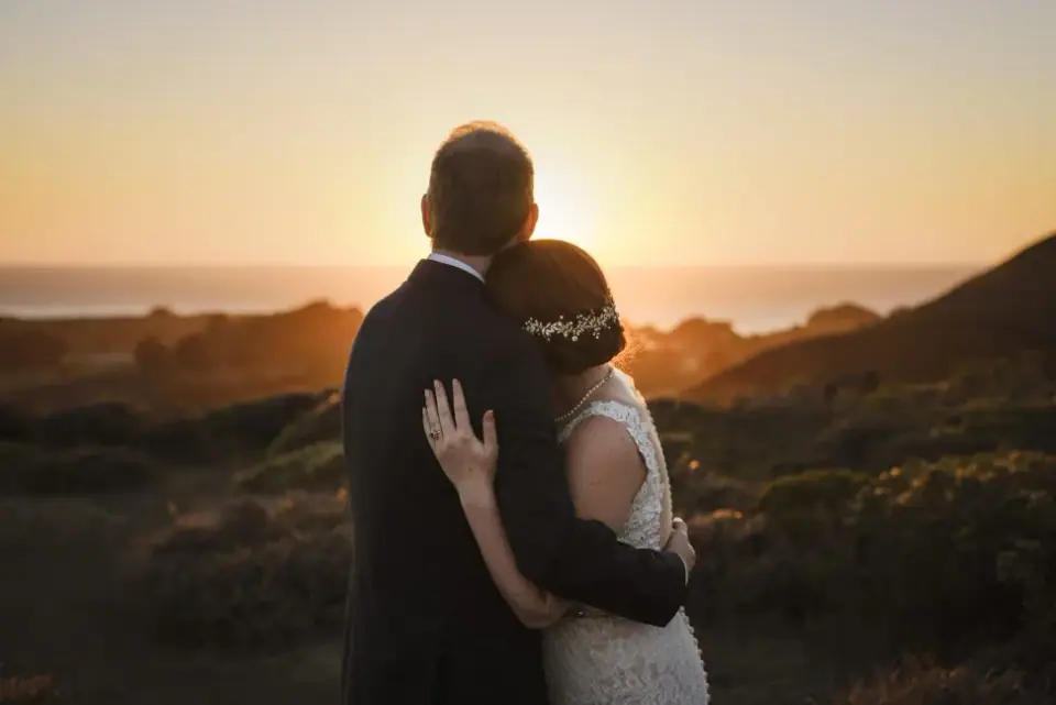Newlyweds embracing in the last orange light