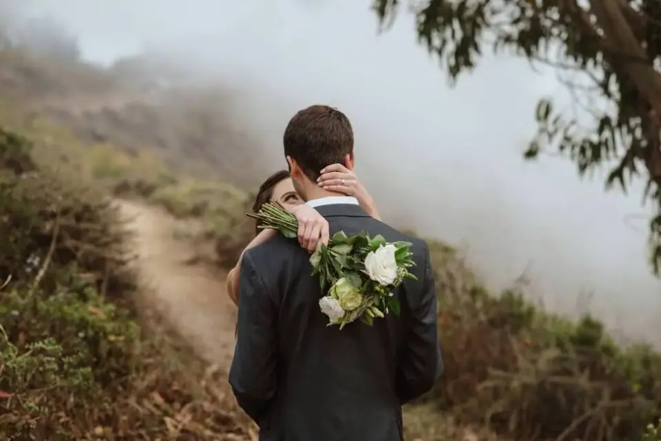 A couple holding each other beneath a coastal tree