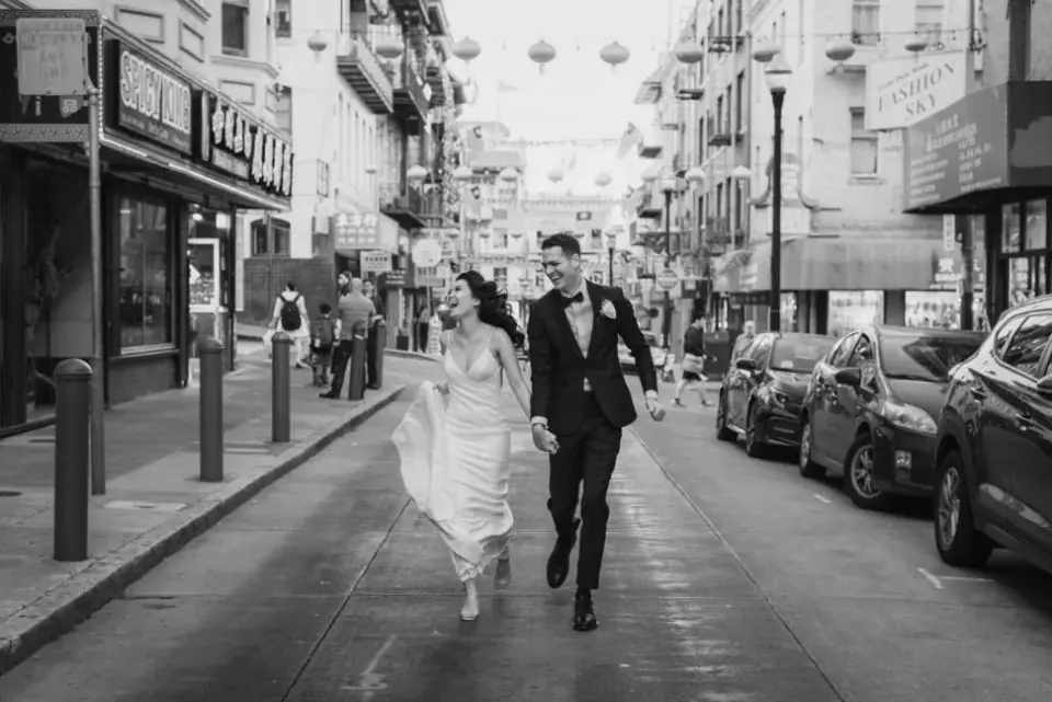 Newlyweds running together through San Francisco Chinatown