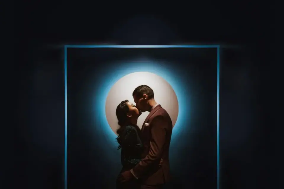 A couple silhouetted inside a circular light artwork