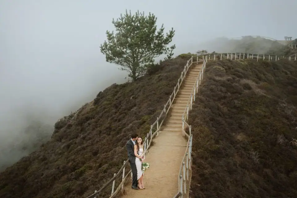A couple at the base of a foggy coastal staircase