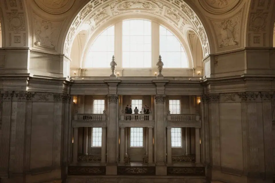 Newlyweds framed by the upper arches of San Francisco City Hall