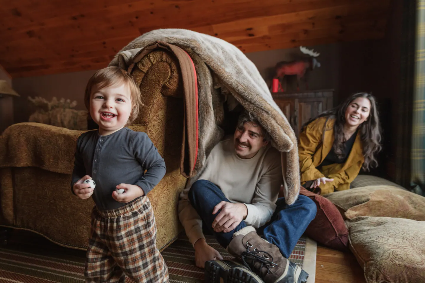A family laughing under a blanket at home
