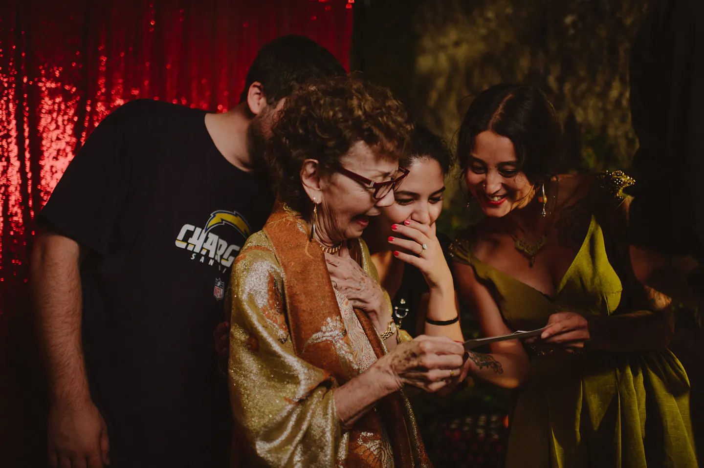 Wedding guests laughing together as they look at a freshly printed photobooth strip