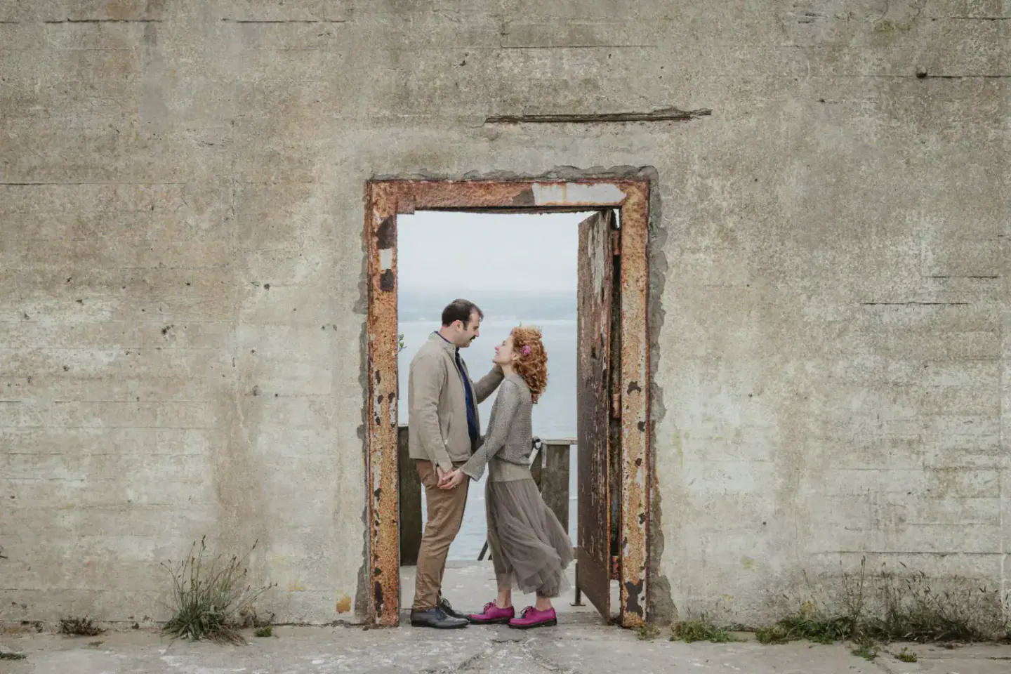 A couple framed by a weathered Alcatraz doorway during their engagement session