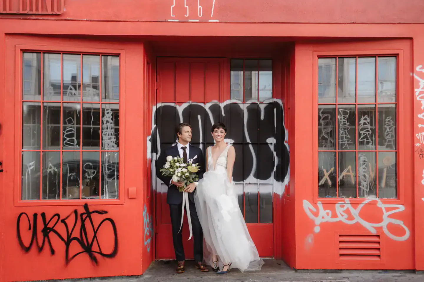 A couple outside a red doorway in Clarion Alley before a Foreign Cinema wedding