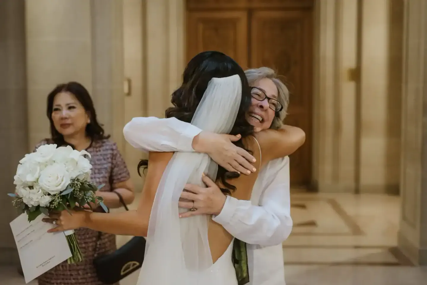 A newlywed embracing a family member after a San Francisco City Hall ceremony