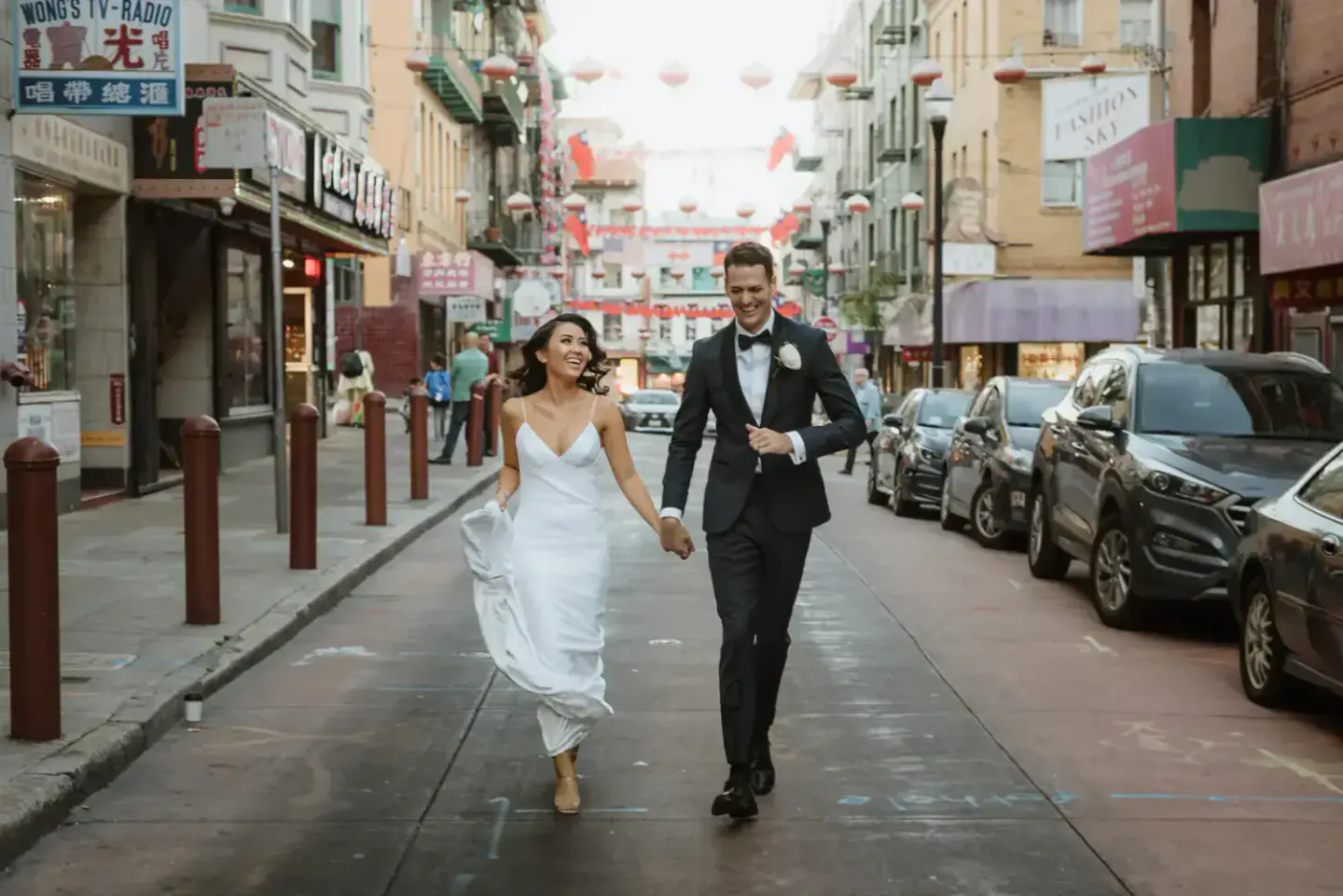 Newlyweds running together through Chinatown after their San Francisco City Hall wedding