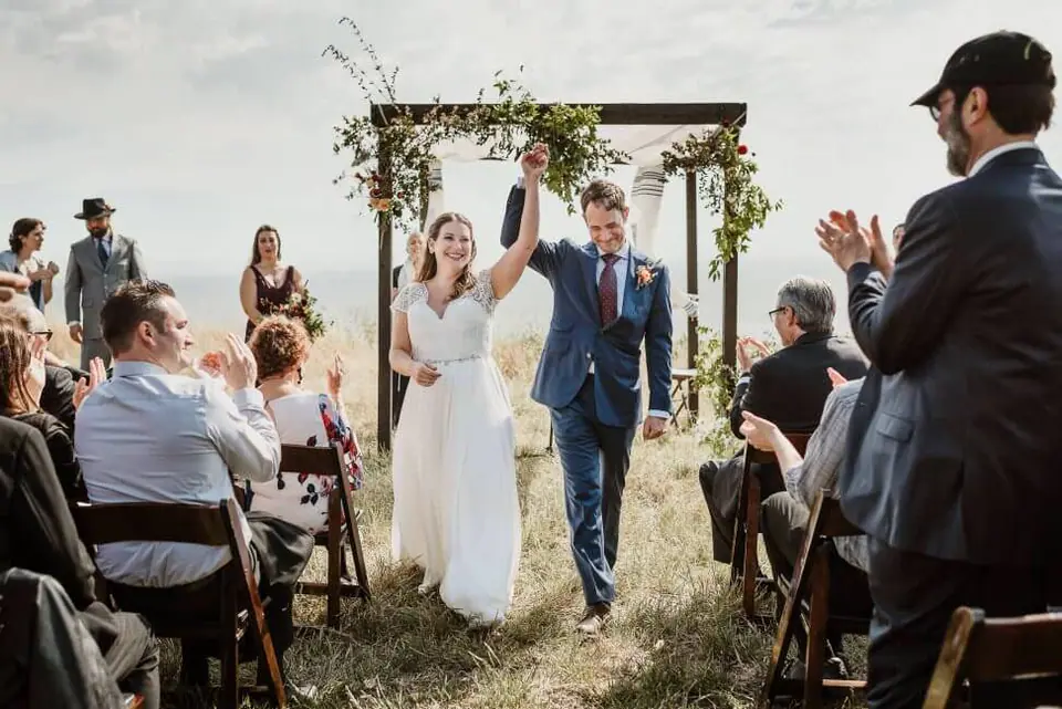 Newlyweds leaving their cliffside ceremony at Slide Ranch in Muir Beach