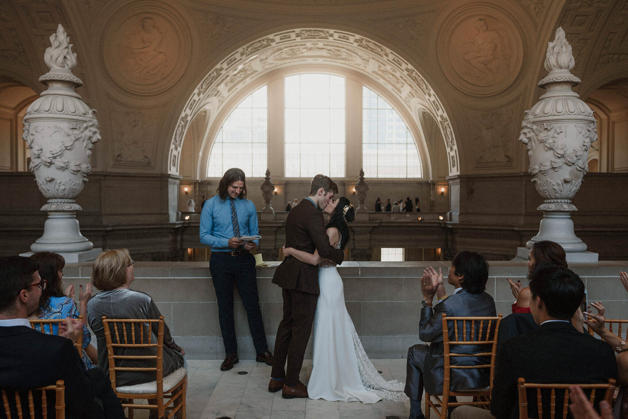A couple exchanging vows with guests in the Fourth Floor Gallery at San Francisco City Hall