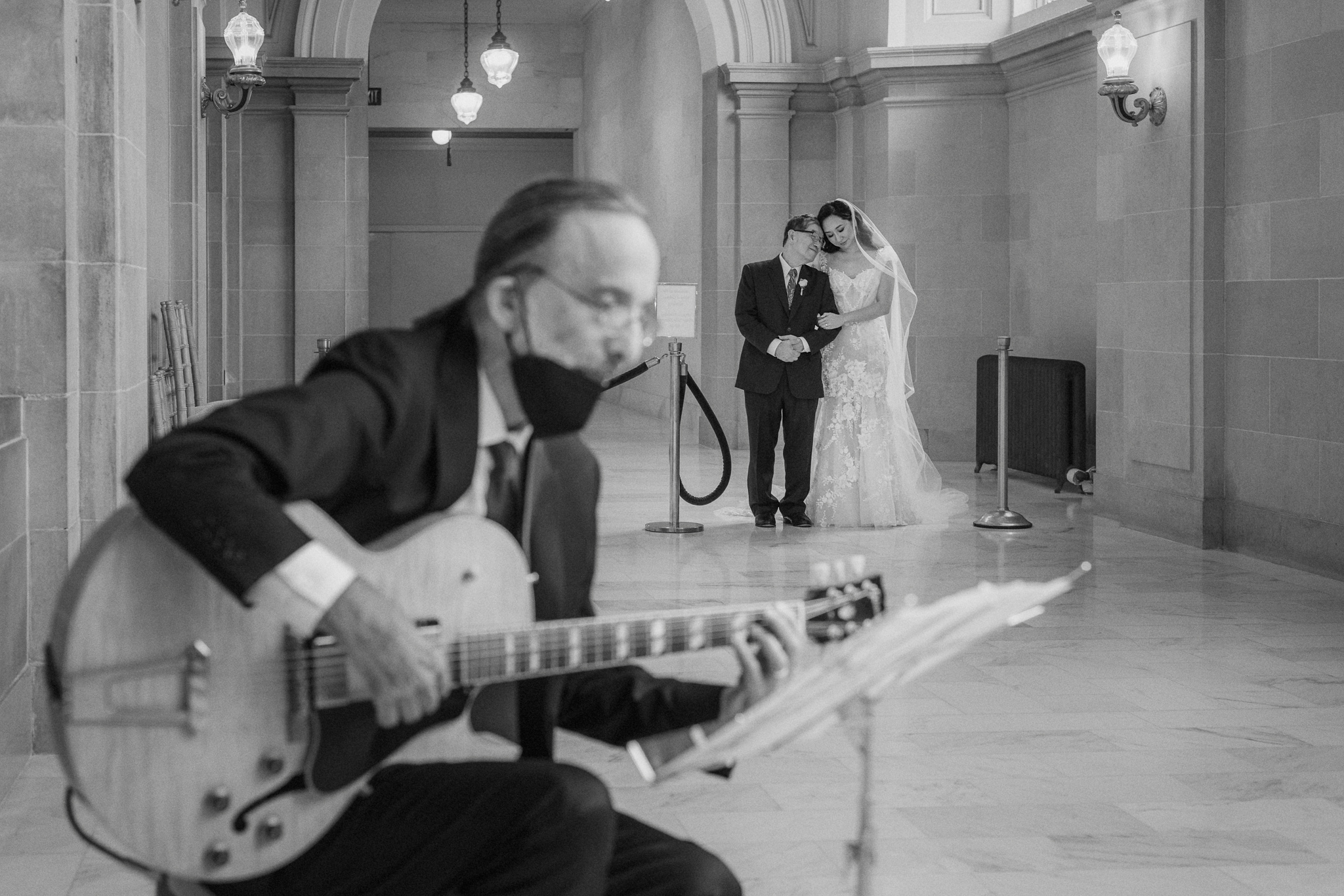 A guitarist performing while newlyweds kiss inside San Francisco City Hall