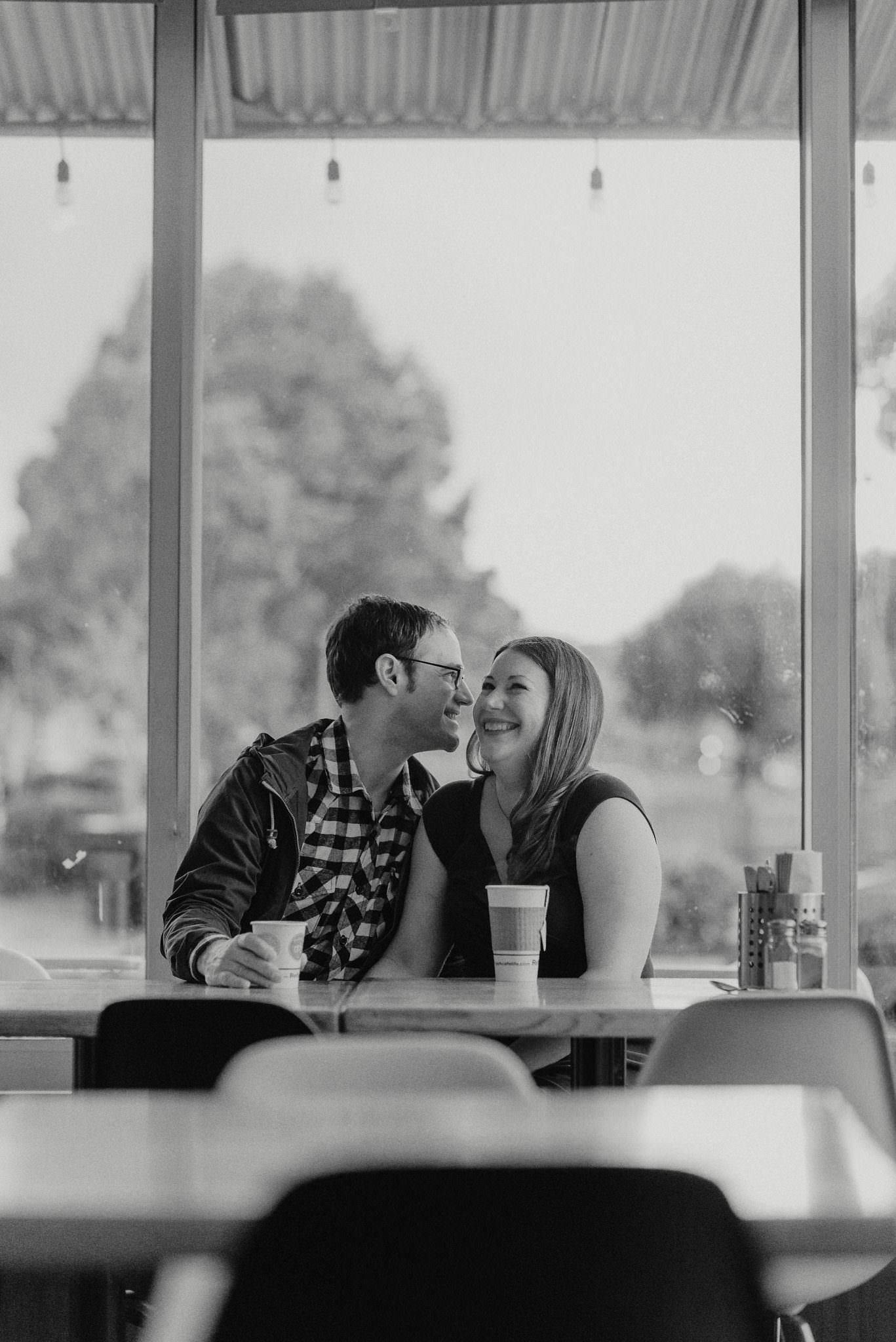 A vertical black-and-white photograph of a couple at a cafe table