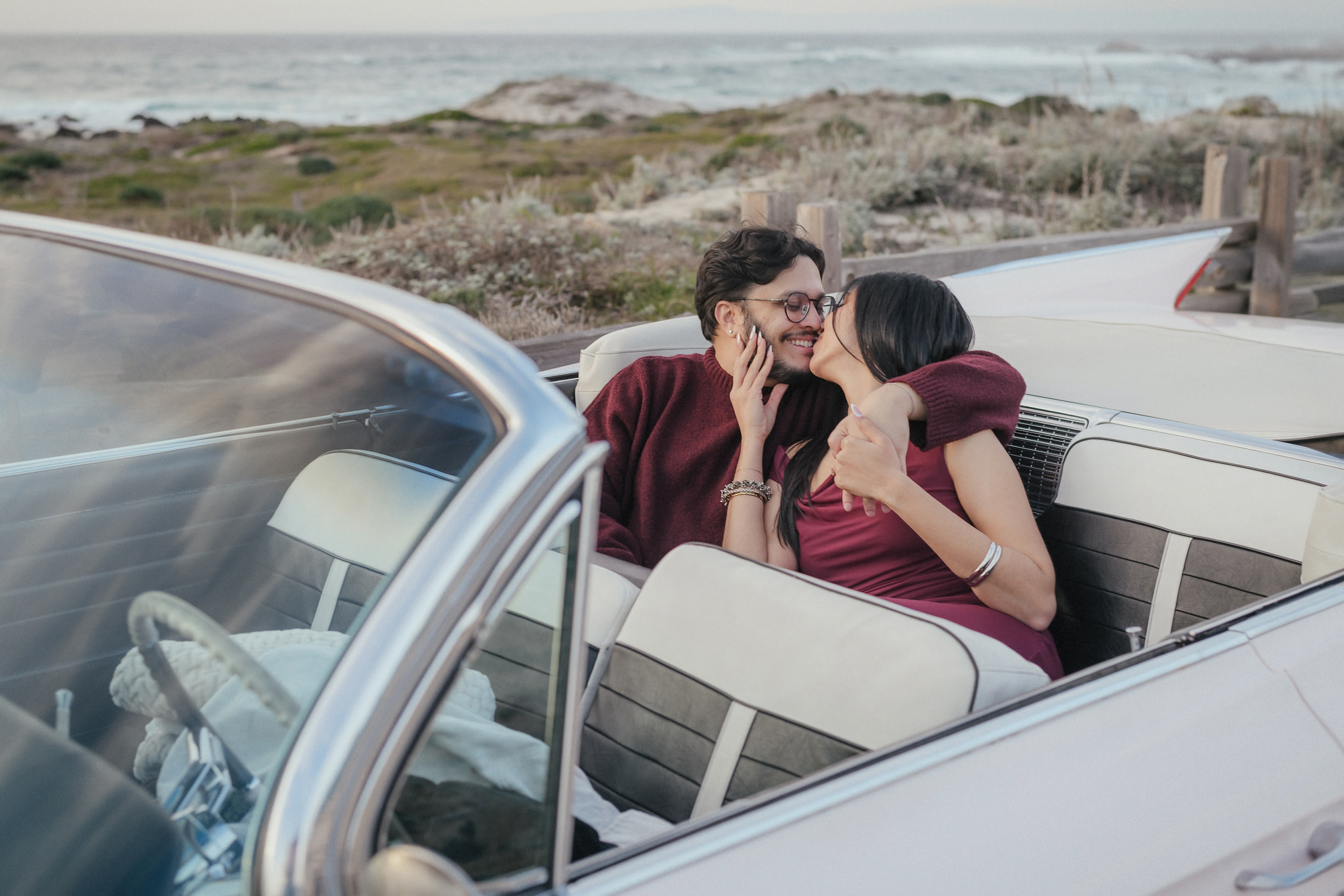 A candid engagement photograph in a vintage convertible