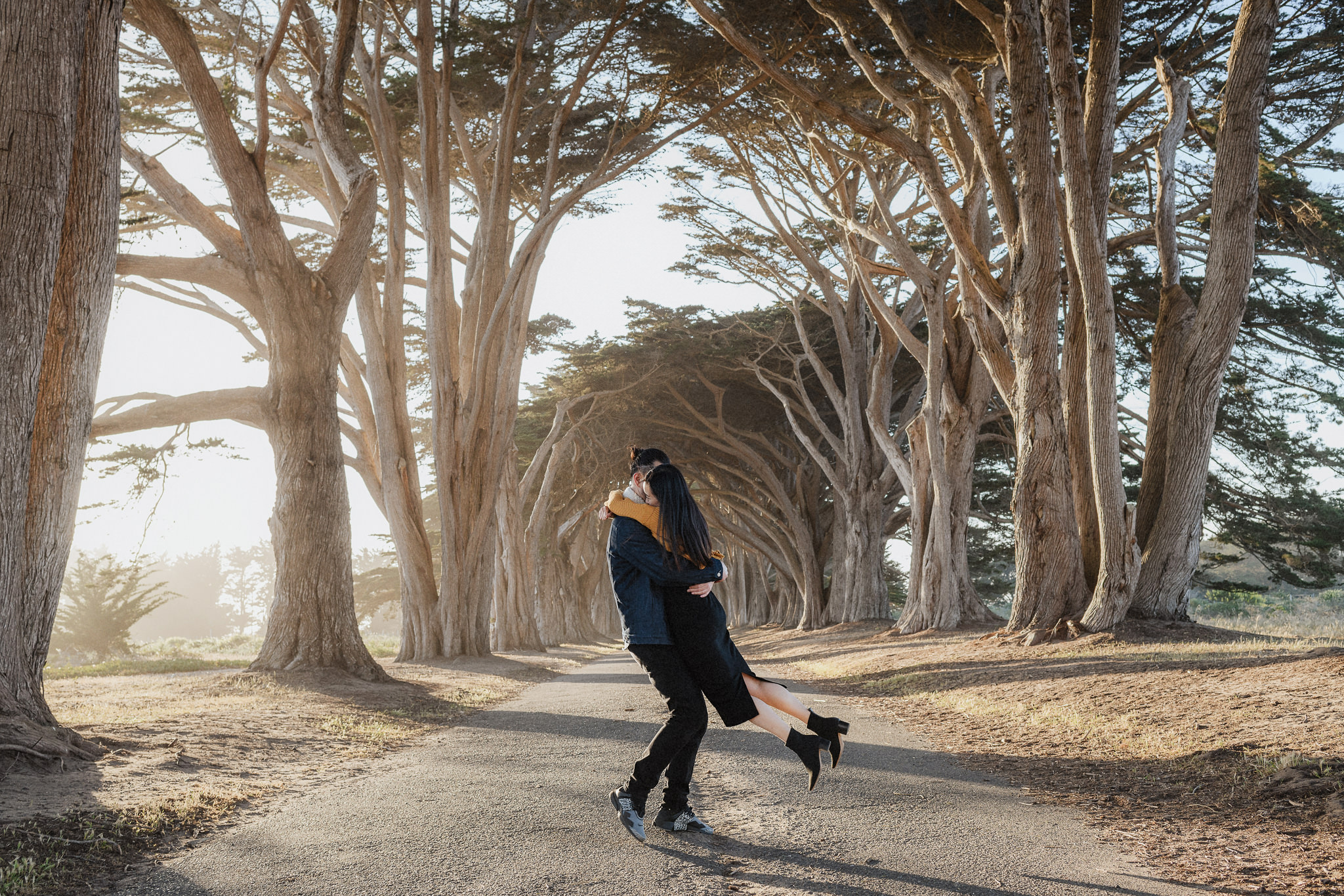 A couple moving together beneath cypress trees during a Bay Area engagement session