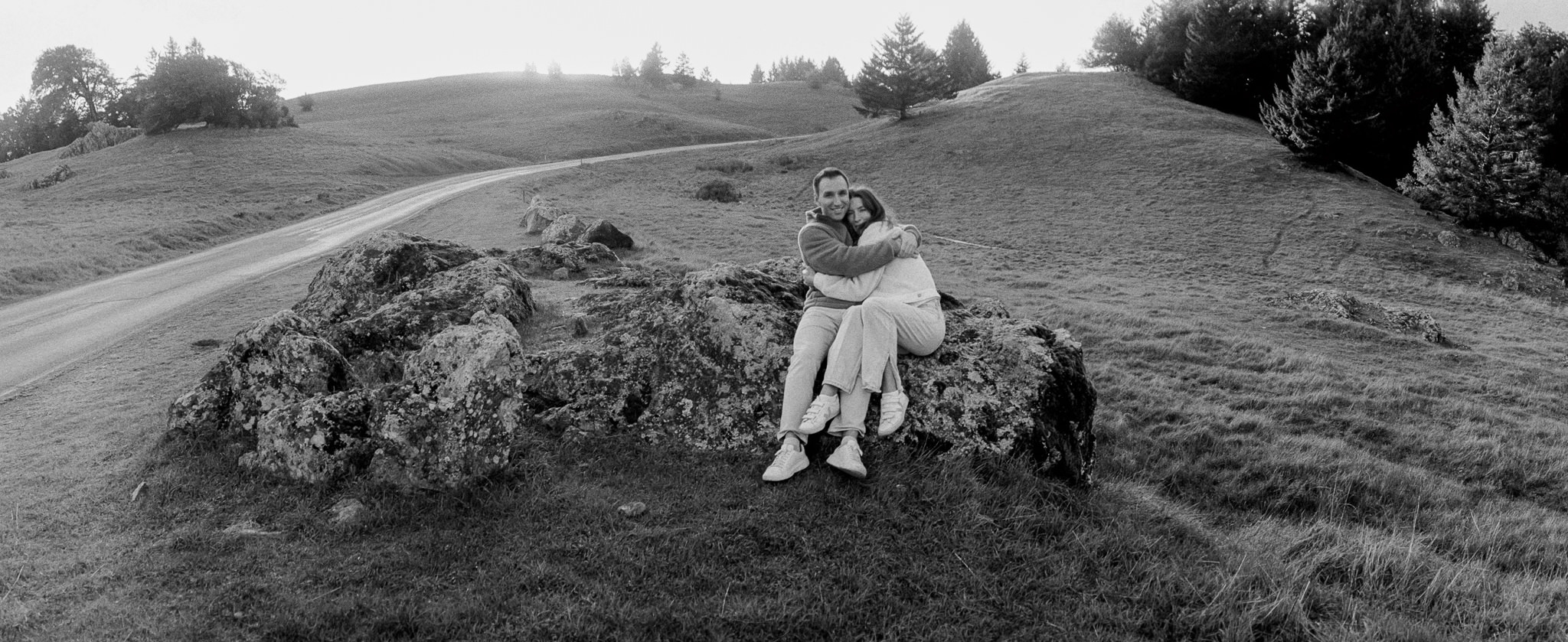 A wide black-and-white engagement portrait in an open landscape