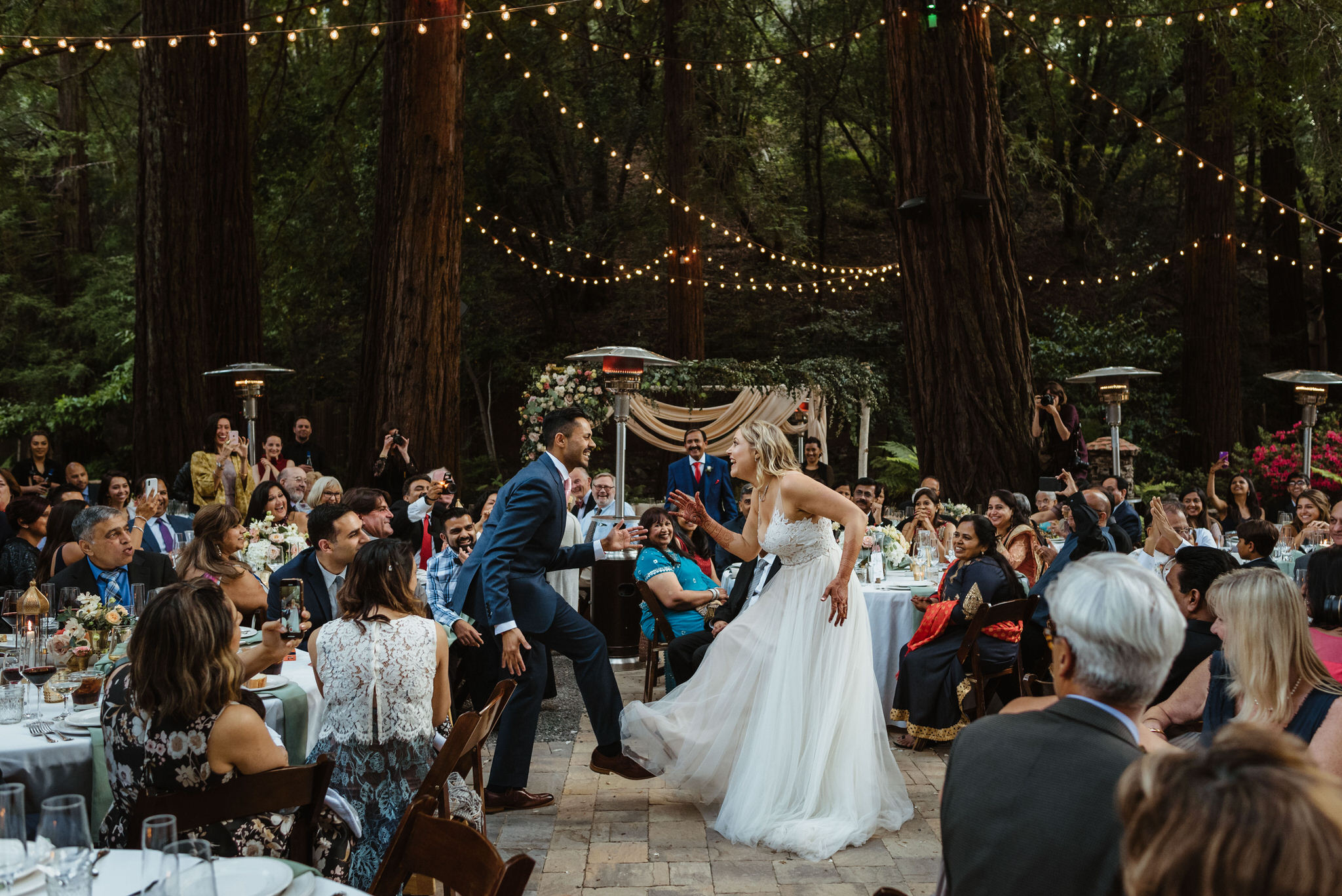 A couple dancing in bright wedding clothes as their guests cheer