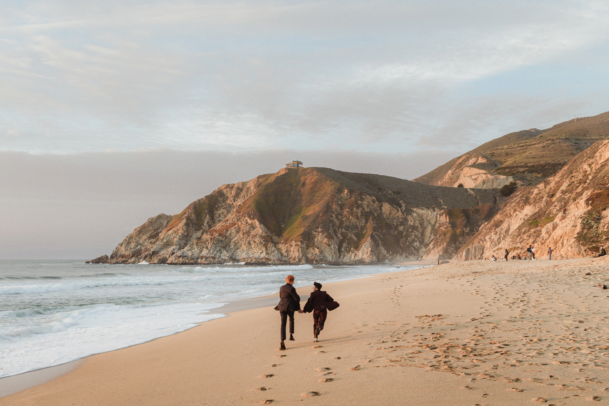 A couple running down the beach hand in hand