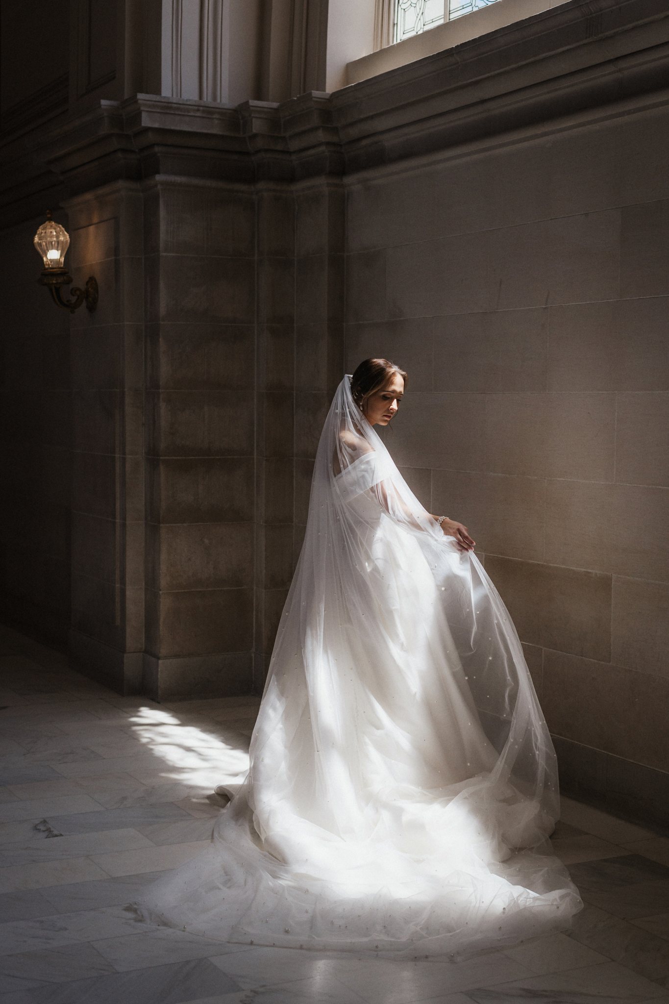 A bride plays in the light on the fourth floor of SF city hall