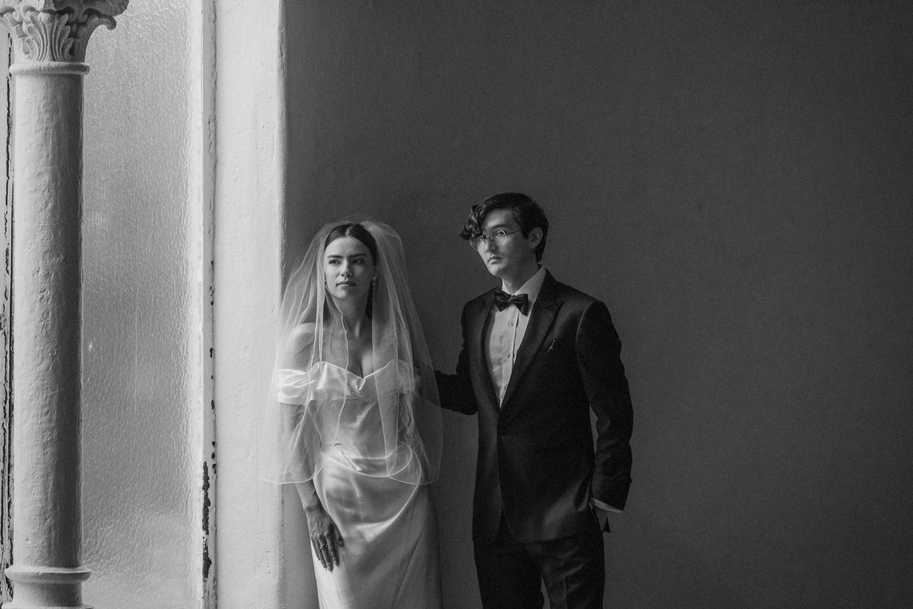 A couple framed by tall windows and layered reflections