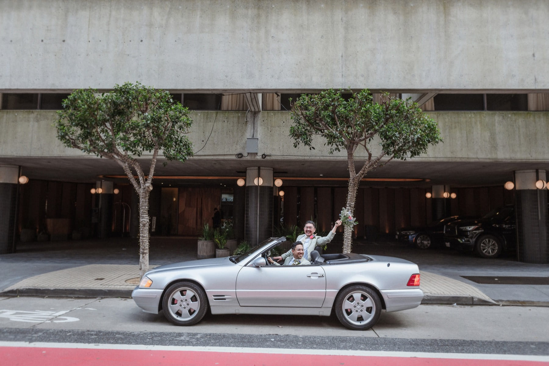 Newlyweds driving away in a convertible in downtown San Francisco