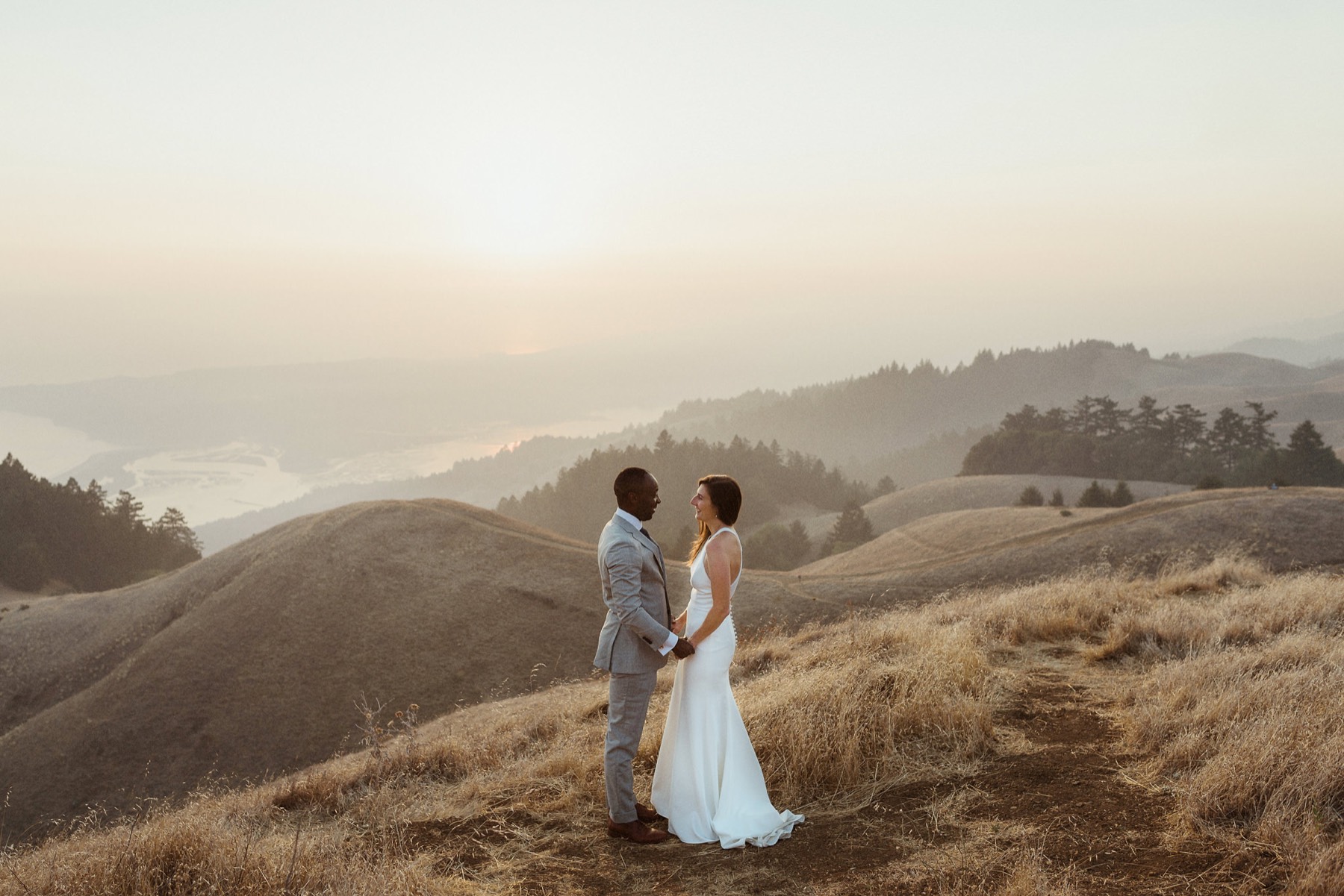 Newlyweds standing together in the late light on Mount Tamalpais